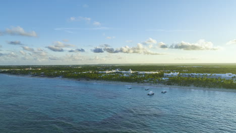 Approaching-drone-shot-of-a-coastal-area-in-the-island-of-the-Dominican-Republic,-passing-by-some-sailboats-and-yachts-at-the-beachfront