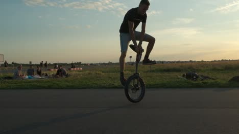 A-young-and-energetic-boy-balancing-on-a-unicycle-in-evening-in-public-park