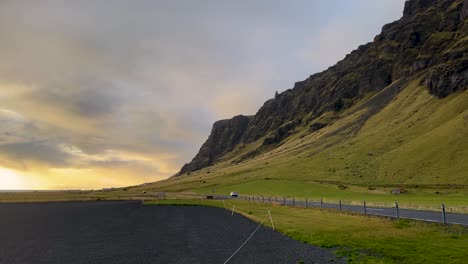 Coche-Conduciendo-Por-Una-Pintoresca-Carretera-Rural-Junto-A-Acantilados-En-Islandia-Al-Atardecer