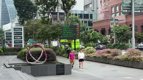 People-stroll-along-Orchard-Road,-and-the-background-reflects-the-available-LED-Car-Park-lots-signs-at-various-malls-in-Singapore