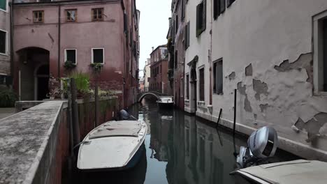 Quiet-navigable-channel-in-Venice-Italy-empty-in-the-morning,-docked-boats
