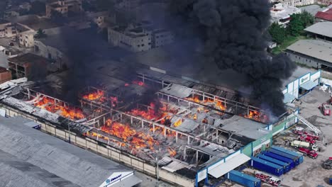 AERIAL:-firefighters-trying-to-quell-a-massive-building-fire,-black-smoke-rising