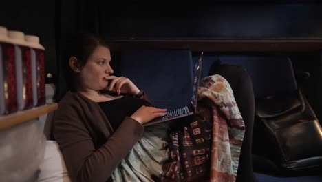 Woman-laying-and-working-in-public-transport-seats-with-her-laptop-laying-on-her-knees,-wide-angle-interior-shot,-train