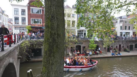 Festive-scene-in-Utrecht,-Netherlands,-during-King's-Day-,-with-people-celebrating-on-a-boat-and-along-the-canal