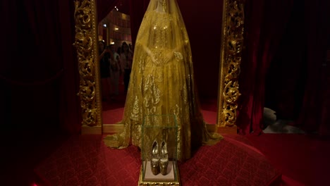 Showcase-of-a-golden-haute-couture-dress-with-intricate-designs-displayed-at-a-high-fashion-exhibition,-featuring-elegant-shoes