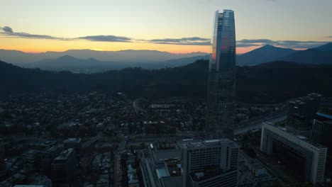 Panoramic-drone-shot-in-front-of-the-Gran-Torre-Santiago,-moody-evenng-in-Chile