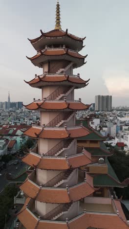 Buddhist-temple-or-pagoda-prayer-tower-in-late-afternoon-light-with-city-skyline-and-urban-sprawl-of-Ho-Chi-Minh-City,-Vietnam