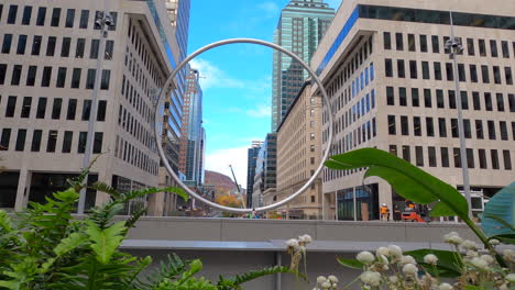 Urban-Circular-Sculpture-Surrounded-By-Buildings-In-Downtown-Montreal-City,-Pedestal-View