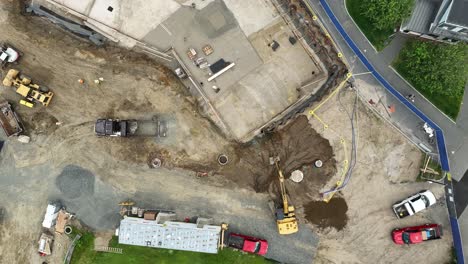 Aerial-top-down-flight-over-large-construction-site-with-excavator-and-truck