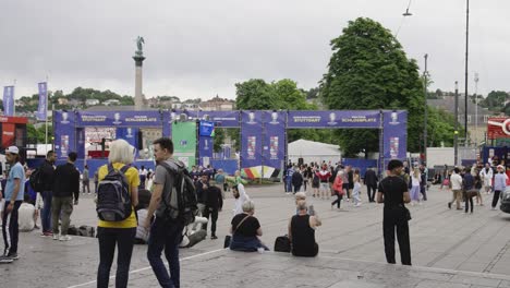 Busy-fanzone-entrance-to-the-Schlossplatz,-Jubilee-Column-in-Stuttgart,-Germany-during-Euro-2024,-people-passing-by-or-sitting-on-stairs,-static-shot-with-copy-space,-nearby