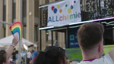 People-waving-Pride-flag-as-floats-pass-by-during-Pride-parade