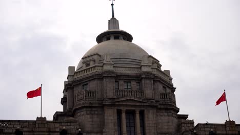 Symmetrical-Chinese-flags-and-dome-of-HSBC-Building-at-The-Bund-in-Shanghai,-China