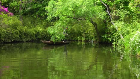 Gardener-in-boat-cleaning-pond-water-at-Humble-Administrator's-Garden-in-Suzhou,-China