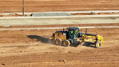 Aerial-overview-of-a-grader-moving-around-on-the-dirt-of-a-new-residential-construction-site