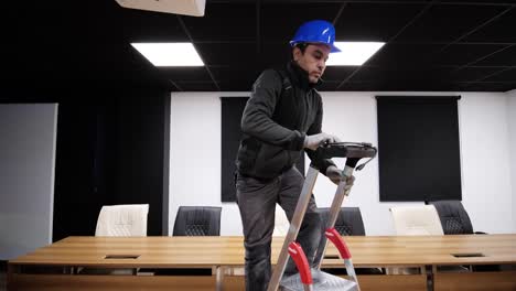 Trabajador-De-La-Construcción-En-Una-Escalera-En-Una-Moderna-Sala-De-Conferencias,-Preparándose-Para-Una-Instalación