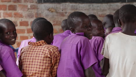 Niños-Pequeños-Estudiantes-Sentados-En-Una-Clase-En-Una-Escuela-En-Una-Remota-Aldea-Rural-De-África,-Sistema-Educativo-Escolar,-Mirando-Detrás-De-La-Cámara