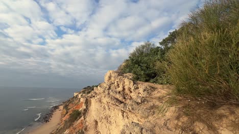 Die-Zerklüftete-Küste-Spaniens-Besticht-Durch-Einen-Sandstrand-An-Sedimentären-Klippen,-Die-Alle-Von-Der-Hellen-Tagessonne-Beleuchtet-Werden-Und-Die-Essenz-Der-Küstenschönheit-Und-Des-Naturwunders-Einfangen