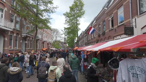 Festive-street-market-in-Utrecht,-Netherlands,-during-King's-Day-,-with-people-enjoying-the-celebrations