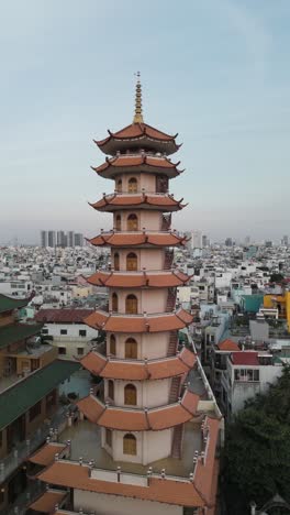 Buddhist-temple-or-pagoda-prayer-tower-in-late-afternoon-light-with-city-skyline-and-urban-sprawl-of-Ho-Chi-Minh-City,-Vietnam