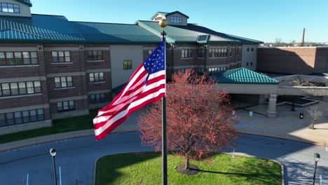 American-flag-waving-in-front-of-high-school-during-sunny-day-in-spring