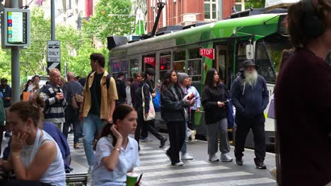 Influx-of-passengers-disembarking-and-boarding-the-tram-at-the-stop-on-Swanston-street-in-front-of-Melbourne-Central-Station-in-the-bustling-central-business-district,-a-vibrant-urban-lifestyle