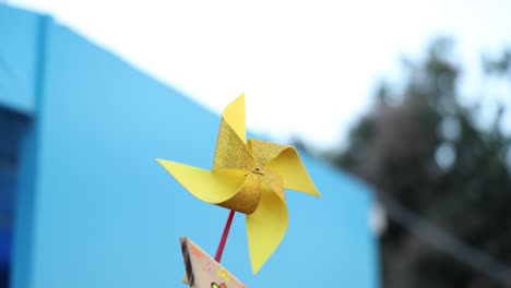 A-bright-yellow-pinwheel-spinning-in-the-breeze,-capturing-a-playful-moment