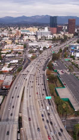 Vertical-Aerial-View-of-Traffic-on-CA-110-Highway,-Harbor-Freeway-by-Downtown-Los-Angeles,-California-USA