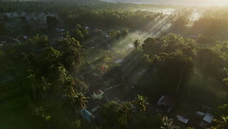 Drone-flying-over-farm-land-and-a-small-village-during-sunrise