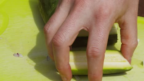 Männliche-Person-Schneidet-Bio-Zucchini-Gemüse-Im-Sonnenlicht-Im-Freien-Mit-Der-Hand-In-Zwei-Hälften---4K-Zeitlupe
