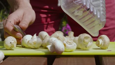 Organic-Baby-Button-Mushrooms-Tipped-onto-Chopping-Board-by-Man-Chef-Holding-Knife-Ready-to-Cut-and-Cook---4K-Slow-Motion-Food-Preparation-Footage