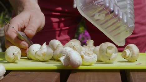 Champiñones-Orgánicos-Para-Bebés-Inclinados-Sobre-Una-Tabla-De-Cortar-Por-Un-Chef-Que-Sostiene-Un-Cuchillo-Listo-Para-Cortar-Y-Cocinar---Imágenes-De-Preparación-De-Alimentos-En-Cámara-Lenta-De-4k