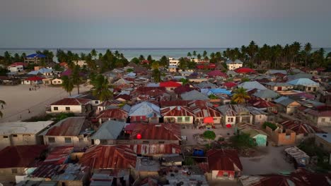 "Explore-picturesque-Paje-town,-Zanzibar:-palm-trees,-blue-rooftops,-distant-mosque,-vast-sand-sports-ground