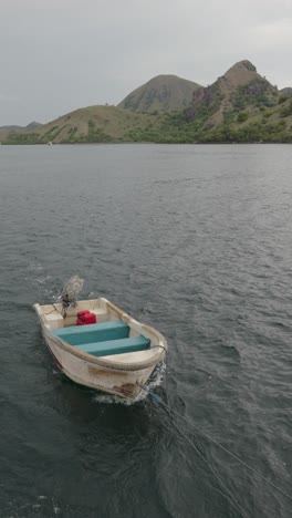 Begeben-Sie-Sich-Auf-Eine-Visuelle-Reise-Durch-Die-Geschäftigen-Gewässer-In-Der-Nähe-Von-Labuan-Bajo,-Indonesien,-Wo-Ein-Traditionelles-Boot-Anmutig-Durch-Die-Malerische-Küstenlandschaft-Navigiert-Und-Die-Essenz-Des-Maritimen-Lebens-Einfängt