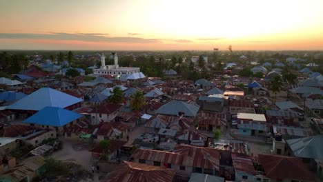 Observe-Cómo-El-Dron-Vuela-Hacia-La-Mezquita-De-La-Ciudad-De-Paje-Al-Anochecer,-Con-El-Sol-Poniendo-El-Cielo-En-Llamas-En-Tonos-Amarillos-Y-Rojos.