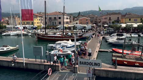 Toma-POV-Desde-El-Ferry-Que-Muestra-A-Un-Turista-Esperando-En-El-Embarcadero-De-La-Ciudad-De-Bardolino,-Italia.