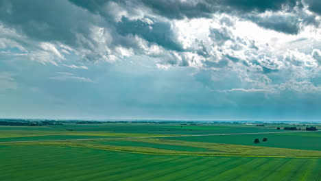 Luftaufnahme-Einer-Drohne-Mit-Hyperlapse-über-Der-Bewegung-Von-Regenwolken-über-Grünen-Feldern-Entlang-Der-Ländlichen-Gegend-An-Einem-Bewölkten-Tag