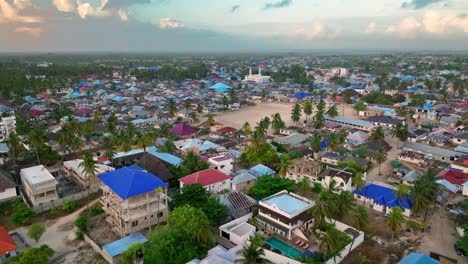 Discover-picturesque-Paje-town,-Zanzibar:-palm-trees,-blue-rooftops,-distant-mosque,-vast-sand-sports-ground