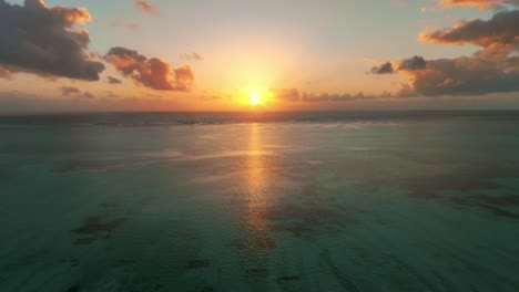 Mavic-3-captures-a-mesmerizing-timelapse-flight-toward-the-setting-sun-over-Paje,-Zanzibar,-painting-the-sky-with-swirling-clouds-above-the-turquoise-ocean-and-coral-reef