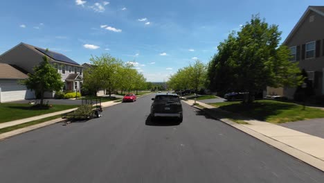 Aerial-following-shot-of-car-on-street-of-quaint-neighborhood-with-green-trees