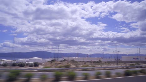 Wide-view-of-Corinth-gas-and-oil-refineries-,-Greece-taken-from-a-traveling-bus,-cloudy-sky-in-the-background-4k