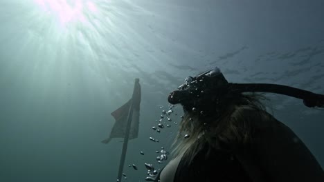 A-woman-dives-up-towards-the-sunlit-surface-near-the-USAT-Liberty-Shipwreck-in-Bali