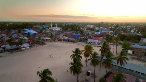 Explore-La-Pintoresca-Ciudad-De-Paje,-Zanzíbar:-Palmeras,-Tejados-Azules,-Una-Mezquita-Distante-Y-Un-Gran-Campo-De-Deportes-De-Arena.