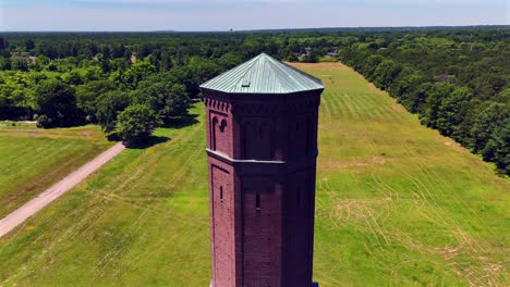 Eine-Luftaufnahme-Eines-Hohen-Gemauerten-Wasserturms-An-Einem-Sonnigen-Tag-Auf-Einem-Großen-Feld-Auf-Dem-Grundstück-Des-Pilger-Psychiatriezentrums-Auf-Long-Island,-New-York