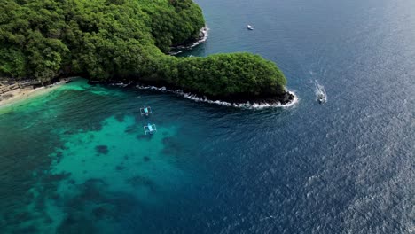 Panning-drone-view-of-the-Blue-Lagoon-in-Bali,-revealing-the-rocky-coast-line,-tradition-boats-with-tourist-in-snorkelling-trips-and-Balinese-temple-on-the-hill