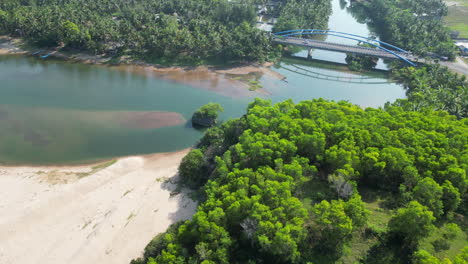 Autos-überqueren-Die-Brücke,-Während-Eine-Drohne-über-Den-üppigen-Dschungel-Und-Den-Blauen-Fluss-Herabsteigt,-Der-Zum-Strand-Pantai-Soge-In-Java,-Indonesien-Führt