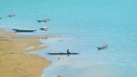 Man-Bathing-On-Wooden-Canoe-Boat-In-The-River---Wide-Shot