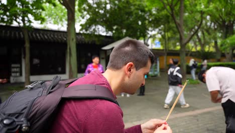 Männlicher-Tourist-Betet-Mit-Brennenden-Räucherstäbchen-Mit-Einheimischen-Chinesen