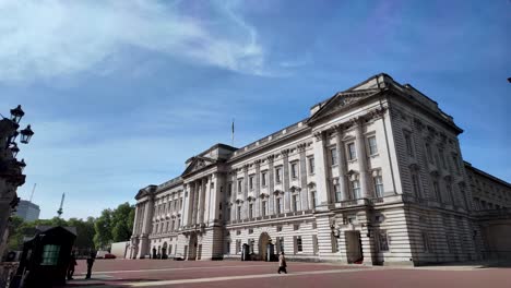 Buckingham-Palace-Mit-Einem-Wunderschönen-Blauen-Himmel-Und-Ein-Paar-Touristen,-Die-Im-Innenhof-Spazieren