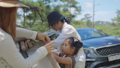 A-close-up-captures-a-heartwarming-moment-of-a-mom-and-her-young-daughter-setting-up-a-tent-on-a-picturesque-pine-covered-hill