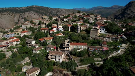 Picturesque-Village-of-Qeparo-with-Old-Stone-Houses-Around-Church-with-Bell-Tower-on-Albanian-Coast,-Facing-the-Sun